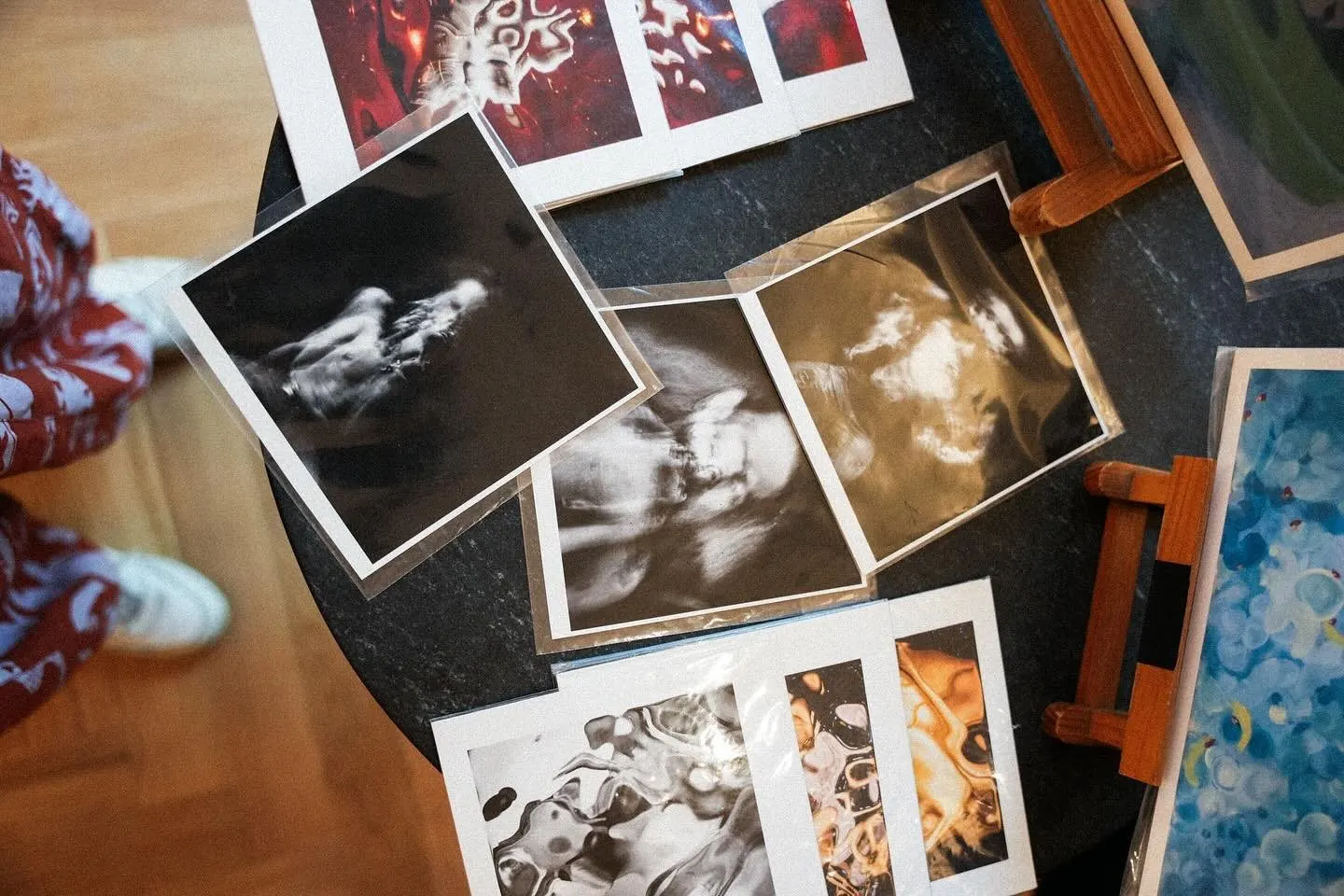 Printed photographs and zines spread across a table at the market
