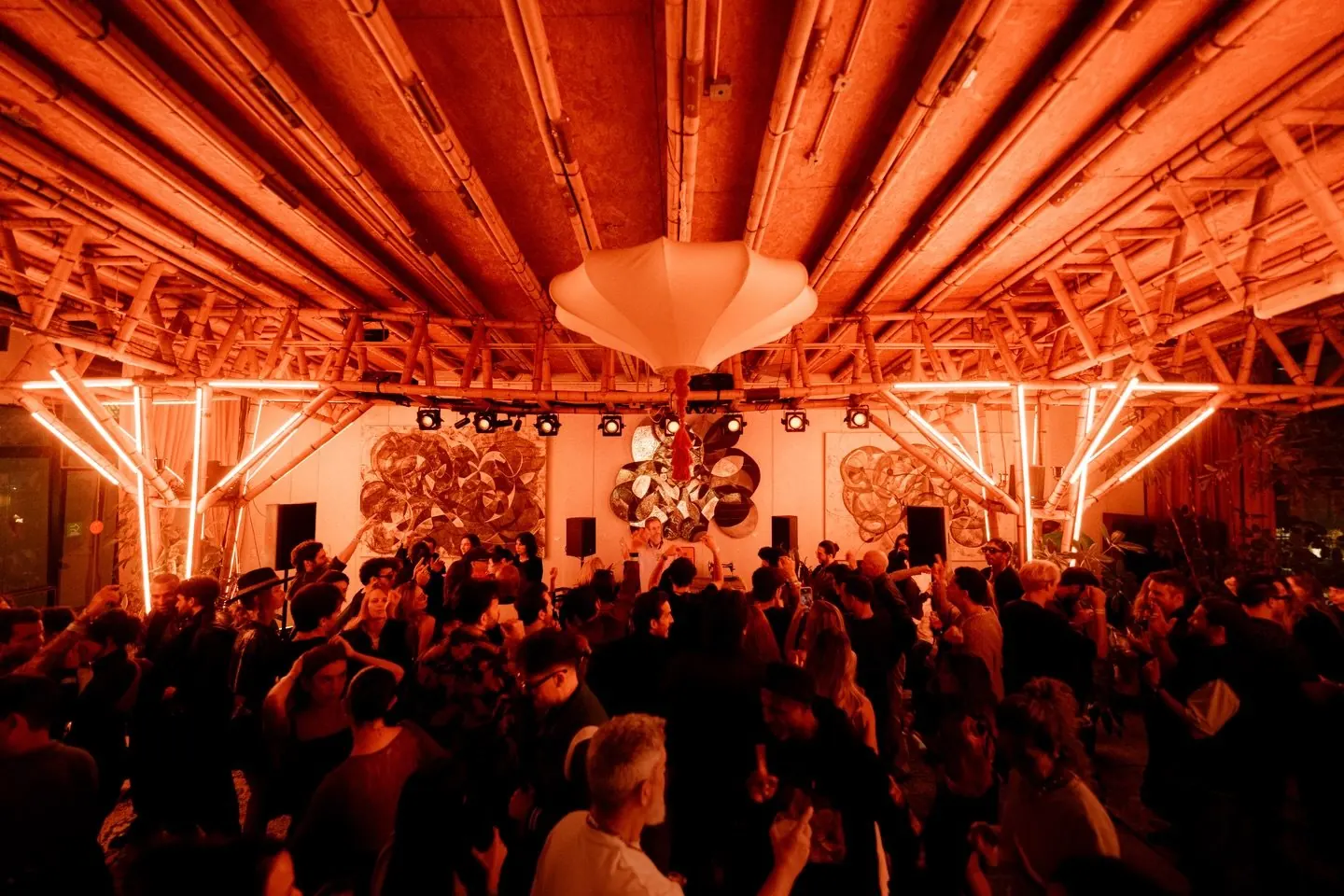 A crowd under an orange-lit ceiling installation during a night at HAAB